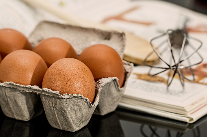 uova di gallina e libro di ricette sullo sfondo