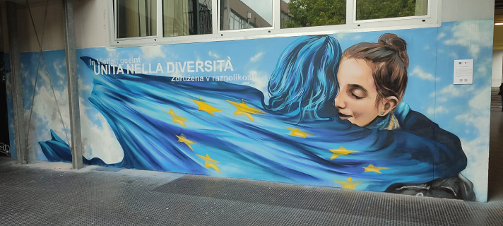 murales di due donne che di abbracciano con bandiera europea