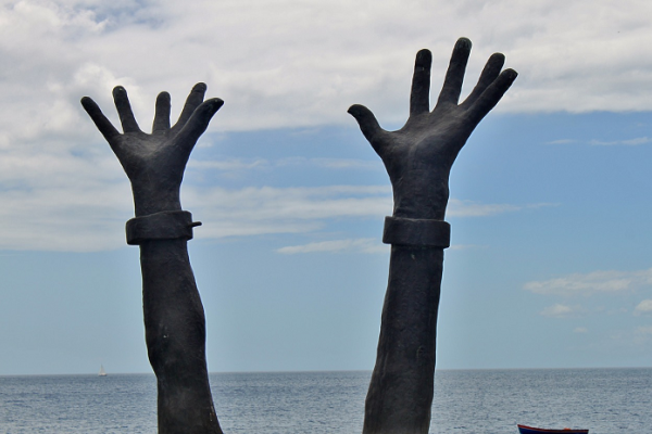 foto di mani  di una statua alzate al cielo con polsi liberi dalle catene