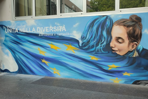 murales di due donne che di abbracciano con bandiera europea